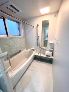 座间味村志摩呼噜呼噜宾馆的白色的浴室设有浴缸和卫生间。