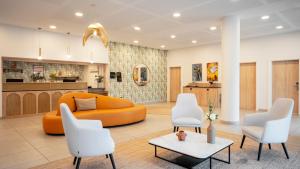尼斯Residhome Nice Aéroport的客厅配有橙色沙发和白色椅子
