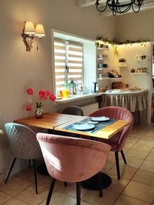 厄里圣彼得Őri Art Inn的厨房配有桌子和一些粉红色的椅子