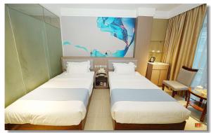 马尼拉pristine848的酒店客房设有两张床,墙上挂有绘画作品