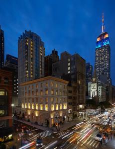 纽约The Fifth Avenue Hotel的繁忙的城市街道,有楼房,夜间有交通