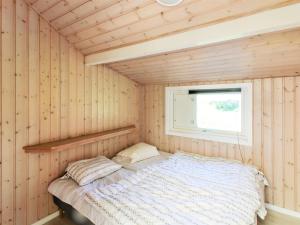 维斯特索马肯Holiday Home Fredrike - 500m from the sea in Bornholm by Interhome的木制客房的一张床位,设有窗户