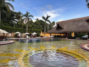圣菲德安蒂奥基亚博通德索酒店的一座带茅草建筑的度假村的游泳池
