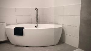 BraunshausenSchneiders Ferienwohnung 2的浴室设有白色浴缸,备有黑色毛巾