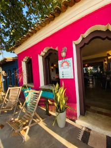 阿拉亚尔达茹达Pousada Anacã的粉红色的建筑,外面设有椅子和桌子