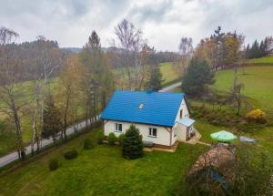 JastrzębiaDomek Wilgówka的绿色田野上带蓝色屋顶的房子