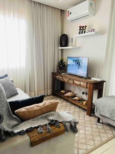 伊达贾伊Apto 2 quartos, completo e aconchegante的客厅配有书桌和电视。