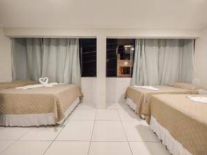马拉戈日Pousada do Alemão的配有2张床的白色地板和窗户的客房