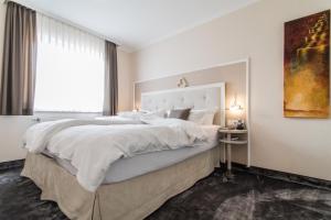 朗格奥Suiten-Hotel mare Langeoog的白色的卧室设有一张大床和一个窗户