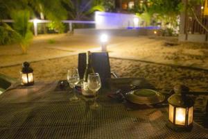 NetolpitiyaBlue Ocean Resort的海滩上配有酒杯和灯的桌子