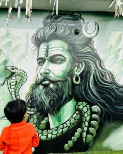 瓦拉纳西Gully Ghar的站在一个男人的蛇画前的孩子