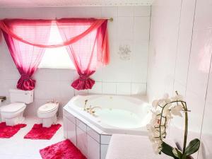 奥拉涅斯塔德Tropical Retreat Stay Aruba的带浴缸、卫生间和粉红色窗帘的浴室