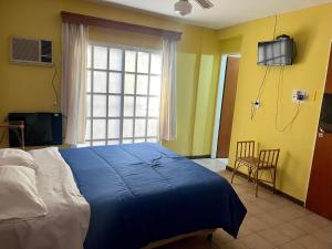 圣胡安Hotel cuesta del viento II的一间卧室配有一张蓝色的床和一台墙上的电视。