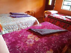 帕纳哈切尔Hospedaje Santo Domingo的客房内的两张床和色彩缤纷的毯子