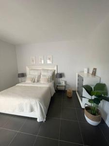 维拉韦德Paraiso的卧室配有白色的床和盆栽植物