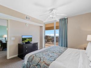 默特尔比奇蒂尔曼海滩和高尔夫度​​假酒店的一间卧室配有一张床、一台电视和一个阳台