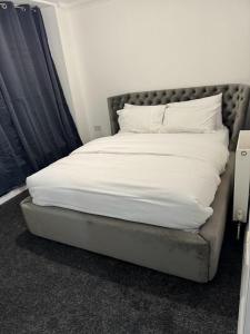 达格纳姆LUXURY APARTMENTS的一张带白色床单和枕头的床