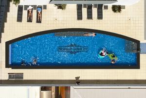 达尔文"NEWQUAY" Ideal Location & Views at PenthousePads的游泳池里有人的建筑物边的广告牌