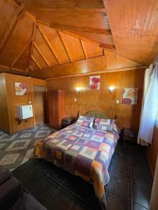 圣何塞德迈波Cabañas Los Olmos的木制客房内的一间卧室,配有一张床