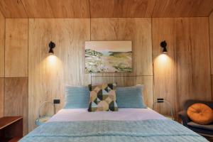 比舍诺Bicheno Garden Cottages的一间卧室配有木墙床