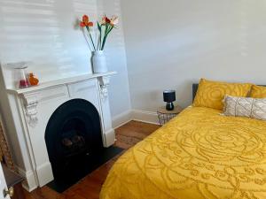 墨尔本Lovely Victorian Terrace - Entire home的一间卧室设有一张黄色的床和一个壁炉
