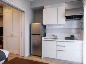 北谷町Family Condo Chatan Hills by Coldio Premium的厨房配有白色橱柜和不锈钢冰箱