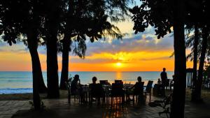 蔻立Baan Khaolak Beach Resort的日落时坐在海滩上桌子上的人