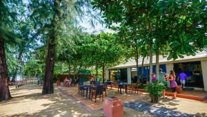 蔻立Baan Khaolak Beach Resort的一群坐在树下桌子的人