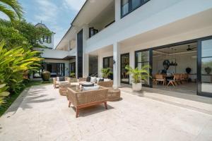 MungguCemagi Beachside Sultana: 5BR Luxury Villa Canggu的户外庭院设有藤椅和桌子。