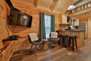 查塔努加Bryce Cabin Lookout Mtn Tiny Home W Swim Spa的小木屋内的厨房设有酒吧凳和平面电视。