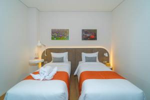 玛琅Se.nandung Living and Space的一间设有两张床铺和毛巾的房间