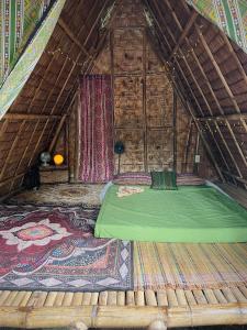DaanbantayanTribal Huts Community的木制客房内的一张绿色大床