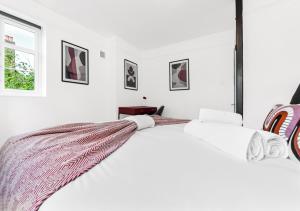 伦敦Radiant Serenity: 2BR Flat Sleeps 5 -Warm Ambiance的白色的卧室,床上有毯子