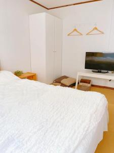 大阪Nippori Osaka Nishi-Tengachaya Guesthouse西天下茶屋アパートメント的卧室配有白色的床和平面电视。