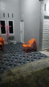 HalanganHomestay Pandan的一张橙色椅子,坐在黑白的格子地板上