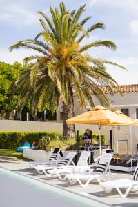 Mindarie明达里滨海酒店的坐在棕榈树旁的伞下的人