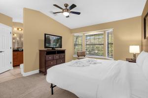 奥兰多4BR. Disney World Vacation Townhome的卧室配有白色的床和吊扇
