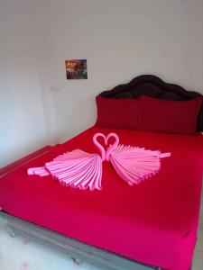 สวนทุเรียน นันนัน มีดี รีสร์อท的一张带粉红色床罩的床铺,带粉红色翅膀