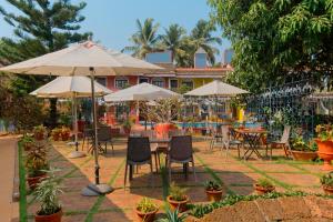 科尔瓦Skylark Resort的一个带桌椅和遮阳伞的庭院