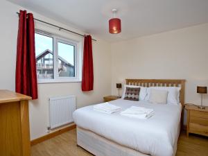 大圣科勒姆Cedar Lodge - Retallack的卧室配有一张带红色窗帘的大型白色床