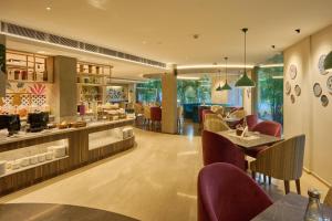 尼杜巴塞莱Flora Airport Hotel and Convention Centre Kochi的一间带桌椅的餐厅和一间酒吧