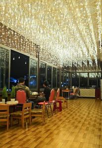 大叻Mai DiaMond Hotel的两人坐在餐厅桌子旁,灯火通明