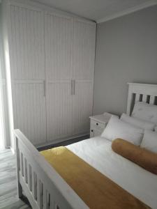 乔治CHARMING GETAWAY的卧室配有白色的床和衣柜。