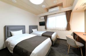 小樽朝里川温泉ホテル的酒店客房设有两张床、一张书桌和一个窗户。