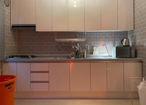 首尔Aufn Orange Bulb的厨房配有白色橱柜和微波炉