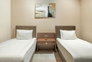 图尔古特雷斯Arin Resort Bodrum的两张床铺位于一个房间,中间有桌子