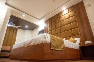 瓦拉纳西Kiran Palace的一间卧室配有一张大床和木制床头板