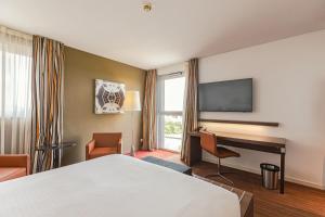 米卢斯米卢斯智选假日酒店的酒店客房配有一张床、一张书桌和一台电视。