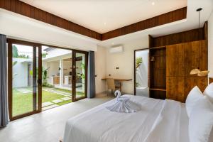 沙努尔J4 Villas Sanur的卧室配有一张白色大床和滑动玻璃门