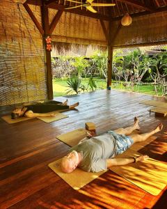 蓝梦岛Island Garden Huts Lembongan的一名在瑜伽课上躺在地板上的男子